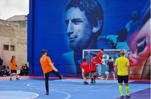 Ragazzi giocano a calcio a cinque della Polisportiva Popolare davanti a un grande murale